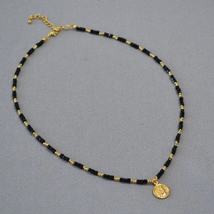 Vintage layered necklace with black spinel beads and gold sun god relief pendant charm