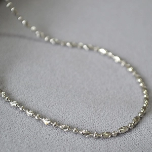 Macro shot of silver bead chain necklace featuring textured oval and smooth round beads