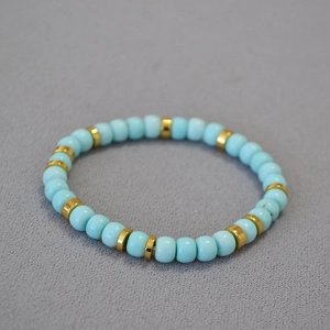 Detailed view of turquoise bead bracelet with golden flat spacers and elastic cord