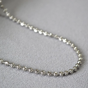 Macro shot of sparkling faceted silver bead necklace with high-polish metallic finish
