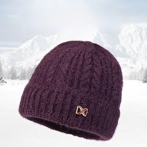 Detail of purple knitted winter hat with thick cable pattern and rose gold buckle decor