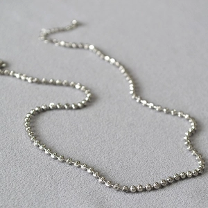 Close-up of a silver beaded chain necklace with a lobster clasp and extension chain