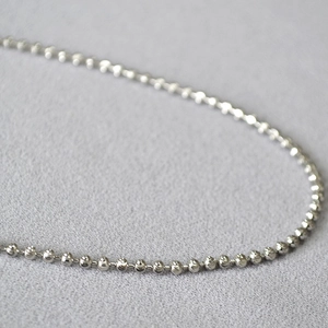 Close-up of polished silver ball chain necklace showing detailed metallic beads