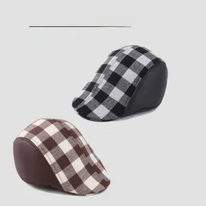 Detail of plaid beret caps with leather brims in black and brown checkered patterns