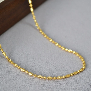 Macro view of gold plated bead chain necklace showing polished oval links and light textures