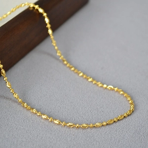 Close-up of sparkling gold bead chain necklace with detailed metal texture and finish