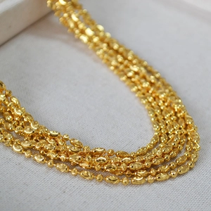 Macro view of five-layered gold beaded chain necklace with textured metal beads
