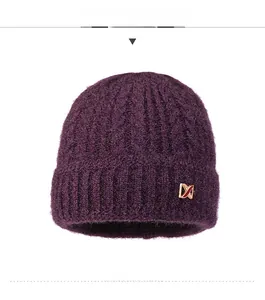 Detailed view of dark purple knit hat featuring thick cable texture and a gold metal logo