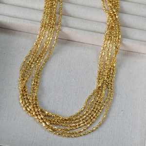 Detailed macro view of multi-layered gold beaded necklace chains in a soft jewelry box