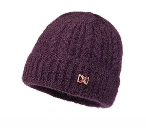 Detail of dark purple knit hat featuring cable pattern and golden butterfly ornament