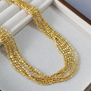 Detailed macro view of a five-layer gold beaded necklace in a luxury velvet display box