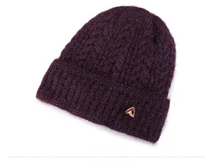 Macro view of dark purple cable knit texture with a small metal bow detail on the hat