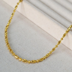 Detailed macro of gold plated faceted bead chain with high polish textured texture finish
