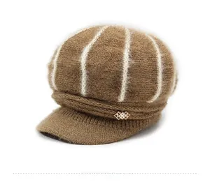 Close-up of brown knit beret featuring thick cable patterns and gold metal ornament