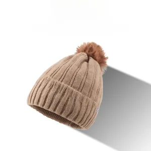 Detail der khakifarbenen Strickmütze mit Bommel, Schachbrettmuster und silbernem M-Logo