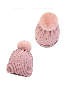 Close-up of pink cable knit hat showing textured weave and premium faux fur pom-pom detail