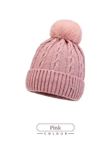 Close-up of pink cable-knit beanie with fluffy pompom and rhinestone H metal logo