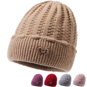 Detail of warm knit winter hat for women featuring a rose gold metal bow pendant