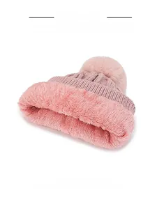 Detail of soft pink fleece lining and fluffy faux fur pompom on a knit winter hat