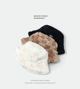 Detail of plush faux lamb wool bucket hats in black and plaid patterns with brand logo