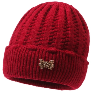 Detailed view of red knitted winter hat with a decorative golden butterfly metal buckle
