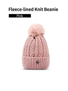 Detail of pink cable knit hat showing plush fleece lining and fluffy faux fur pompom
