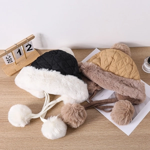 Detail of quilted winter trapper hats with faux fur lining and plush pom-pom ties