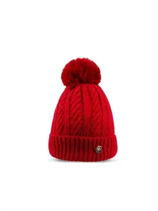 Close-up of red fleece-lined knit hat featuring a gold M charm and large faux fur pom-pom
