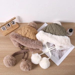 Detail of warm quilted trapper hats in khaki and green with faux fur and pom-pom ties