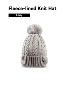 Detail of grey cable knit beanie showing warm fleece lining and fluffy faux fur pompom