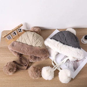 Close-up of quilted trapper hats with thick plush lining and soft decorative pom-poms