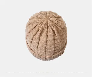 Top down close-up view of beige knitted hat with wave pattern and pearl detail