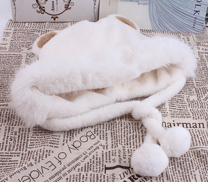 Détail d'un bonnet d'hiver en fausse fourrure crème avec oreilles d'ours et pompons