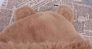 Détail du bonnet oreilles d'ours en peluche douce sur fond de papier journal vintage