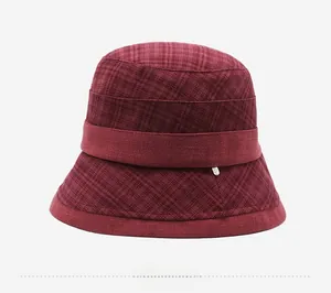 Detail view of burgundy plaid bucket hat with textured fabric and metallic buckle accent