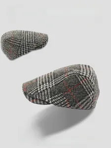 Detailed close-up showing the grey plaid wool texture and red pinstripe of the flat cap