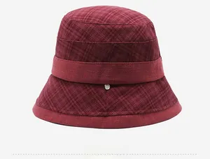 Detail view of burgundy plaid cloche hat with fabric band and small metallic emblem