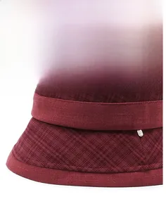 Detail of burgundy checkered woolen hat featuring a firm brim and small metal logo