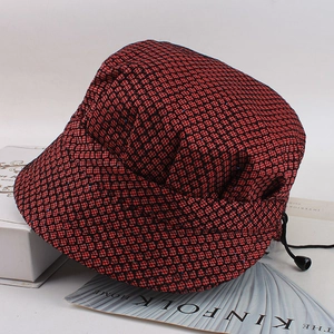 Detail of red and black plaid newsboy hat with subtle blue sequins and adjustable drawstring