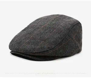 Detail of dark grey herringbone wool texture with red plaid lines on flat cap