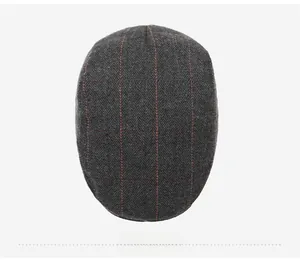 Top view of a grey herringbone wool beret with red plaid lines for autumn and winter