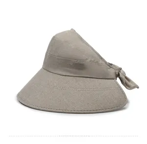 Detail of wide brim sun visor with fine stitching and decorative bow in beige linen