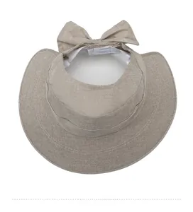Detail of beige linen sun hat featuring a wide brim and elegant bow tie decoration