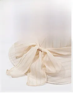 Close-up of beige sun hat with transparent scarf bow and metallic gold stripe details