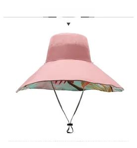 Detail of pink wide brim sun hat with tropical leaf print lining and black windproof cord