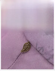 Detailed close-up of a lilac sun hat featuring a decorative bronze hollow leaf metal piece