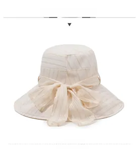 Detailed texture of beige sun hat with fine gold silk threads and a large tulle bow
