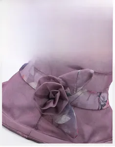 Gros plan d'un chapeau de soleil violet avec fleur en tissu et motifs floraux au bord