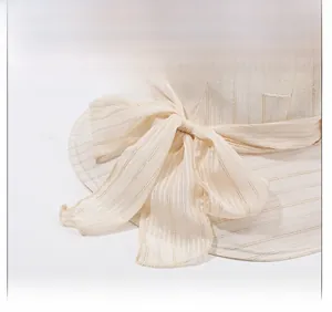 Detail of cream sun hat featuring metallic striped weave and large silk bow tie