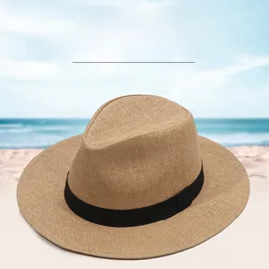 Close-up of woven straw sun hat with black ribbon detail against a beach background